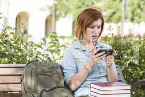 Stunned Young Female Student Outside Texting on Cell Phone