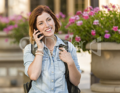 Young Female Student Walking Outside Using Cell Phone