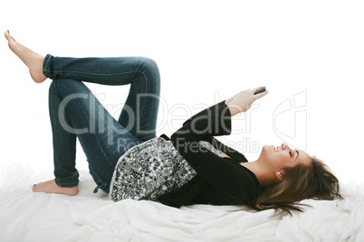 Relaxed young woman sending a text message lying on the bed