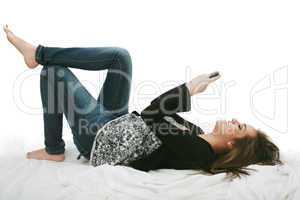 Relaxed young woman sending a text message lying on the bed