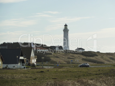 lighthouse in grassland with small village