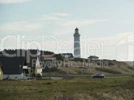 lighthouse in grassland with small village