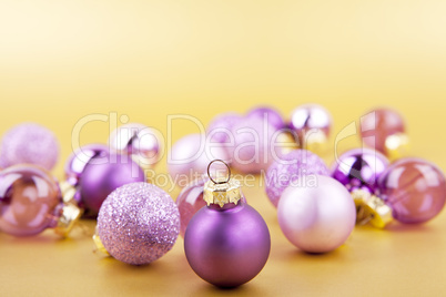 Lila Christbaumkugeln Weihnachtsschmuck auf goldenem Hintergrund