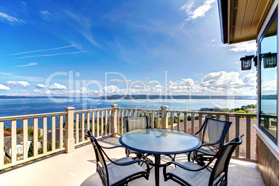 Luxury home balcony deck with water view and table.