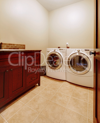 Laundry room with wood cabinets and new appliances.