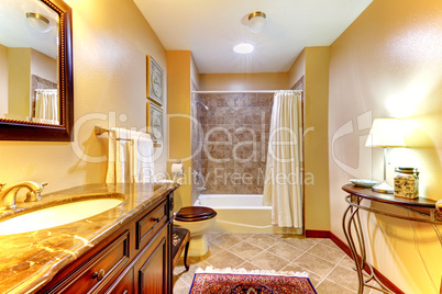 Golden nice bathroom with brown tiles and wood cabinet.