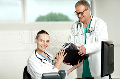Male doctor handing over files to female doctor