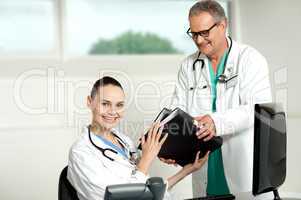 Male doctor handing over files to female doctor
