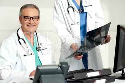 Woman assistant presenting x-ray report to male doctor