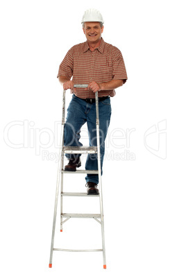 Worker wearing hard hat climbing ladder