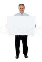 Confident businessman holding blank billboard