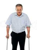 Angry aged man with crutches looking at you