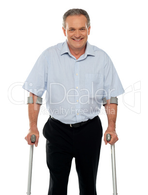 Senior man standing with support of crutches