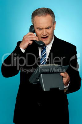 Angry aged corporate man yelling on phone