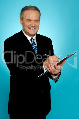 Smiling businessman writing on clipboard