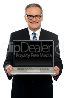 Senior executive standing with open laptop