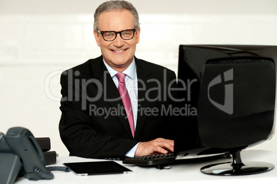 Happy aged corporate man typing on keyboard