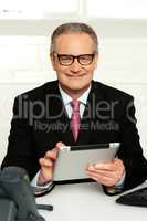 Senior executive sitting with tablet pc in hands