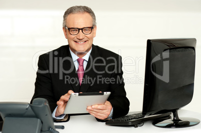 Aged businessman in glasses using tablet
