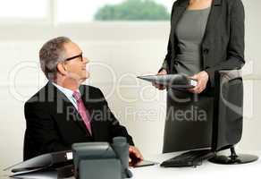 Smiling aged male boss looking at secretary