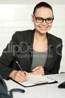 Secretary writing key business notes on clipboard