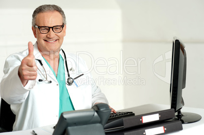 Smiling doctor gesturing thumbs up to camera
