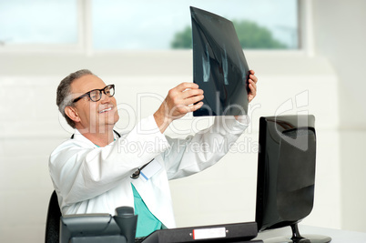 Senior surgeon in glasses looking at x-ray