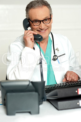 Happy aged medical expert taking on phone