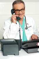 Happy aged medical expert taking on phone