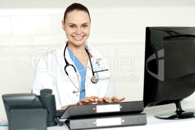 Cheerful female doctor tying on keyboard