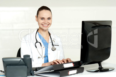 Smiling female doctor working on computer