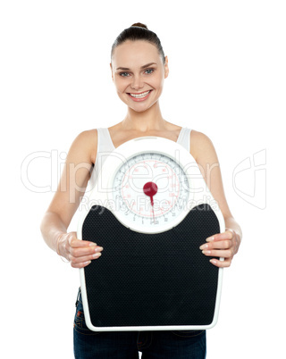 Cheerful young woman holding a weighing