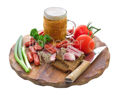 mug of beer and an assortment of salami and vegetables on a cutt