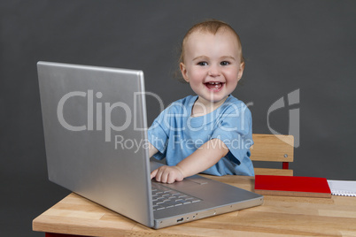 baby with laptop computer in grey background