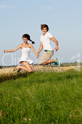 Junges paar springt glücklich in einer Wiese im Sommer
