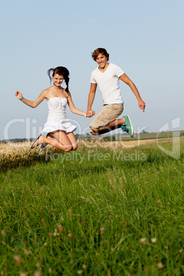 Junges paar springt glücklich in einer Wiese im Sommer