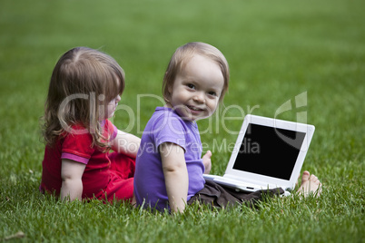Babies with Notebook sitting on meadow