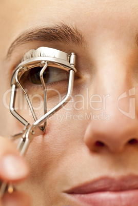 portrait of young woman using an eyelash curler