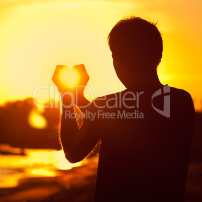 young man holding in hands the setting sun