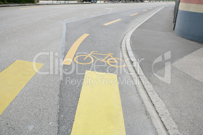Yellow painted sign for bikes on asphalt