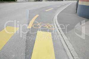 Yellow painted sign for bikes on asphalt