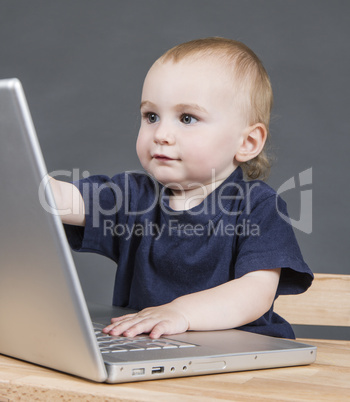 baby with laptop computer in grey background