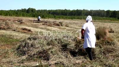Man and woman gather hay in a haystack