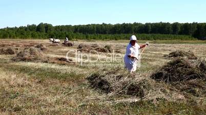 Man and woman gather hay in a haystack.