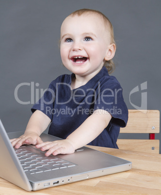 baby with laptop computer in grey background