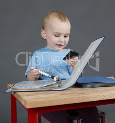 baby with paperwork and calculator at wooden desk