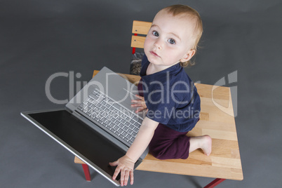 baby with laptop computer in grey background