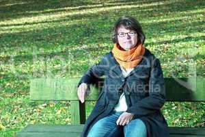 Woman sitting in autumnal park on the park bench