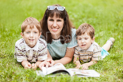 Mother and sons reading book outdoor