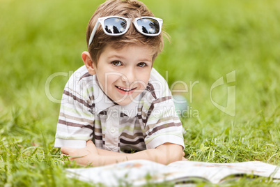 Beauty smiling child boy reading book outdoor